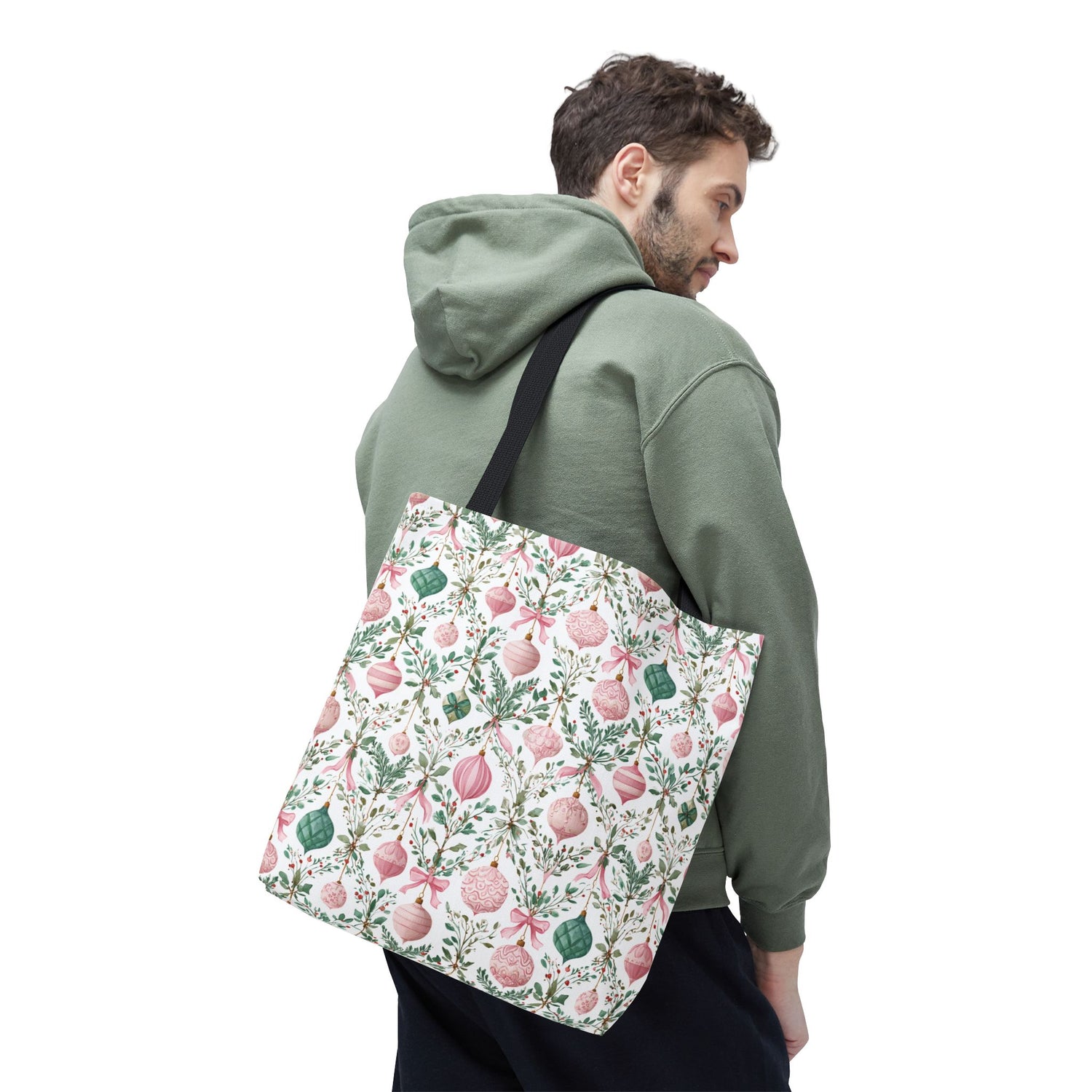 Person wearing a green hoodie with a floral-patterned bag on a white background