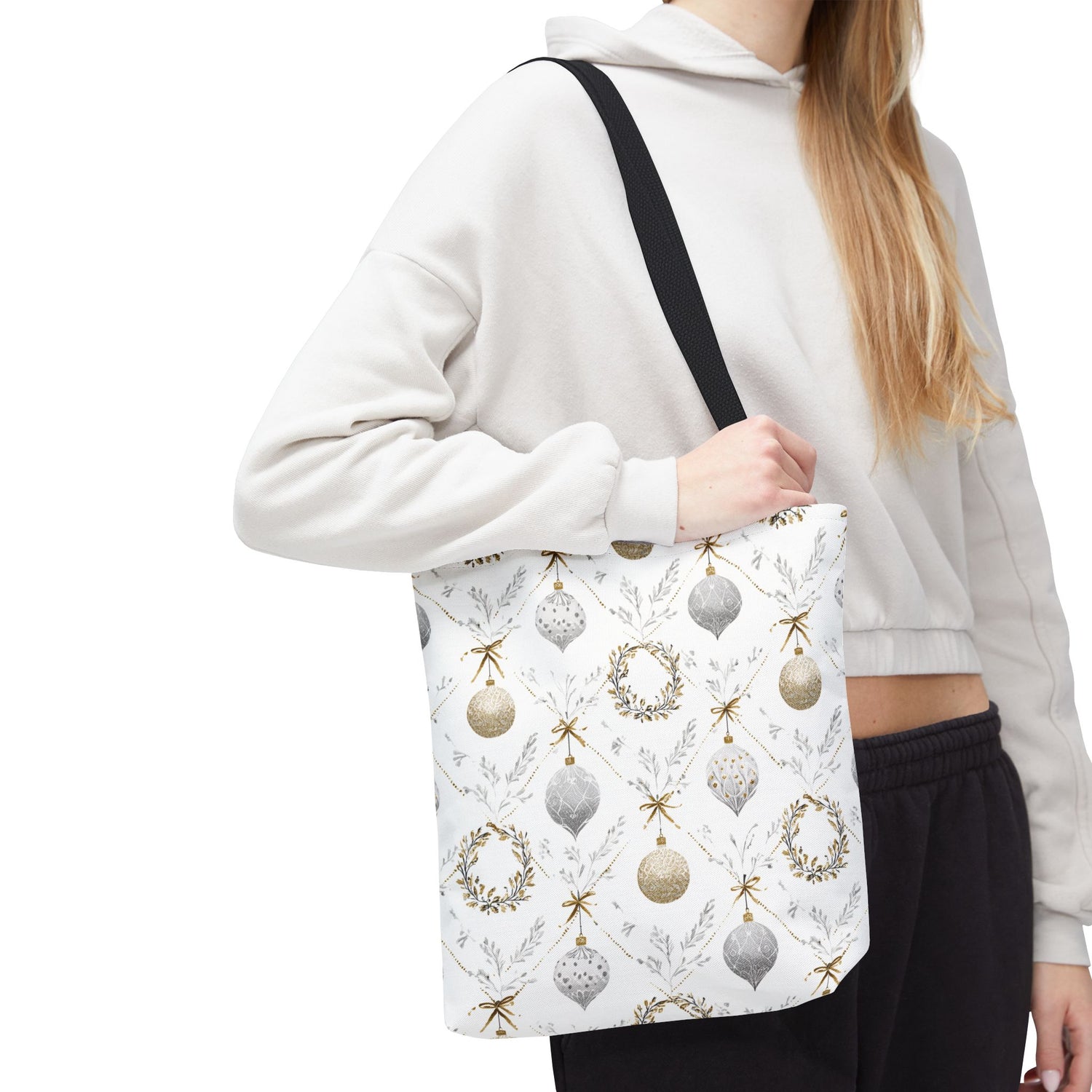 Person holding a tote bag with Christmas ornament design on a white background