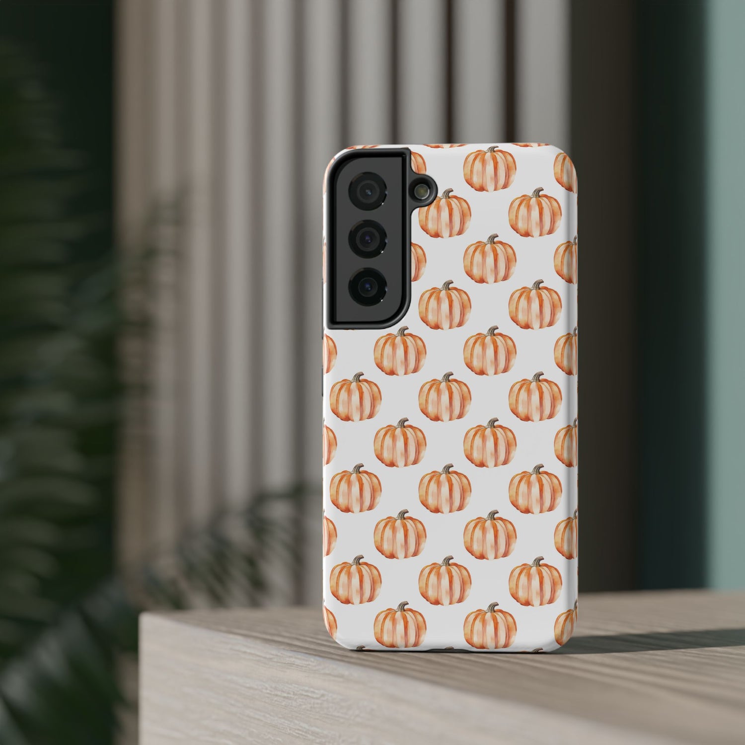 A phone case with a pattern of pumpkins on a white background, featuring a camera cutout and a black border at the top.