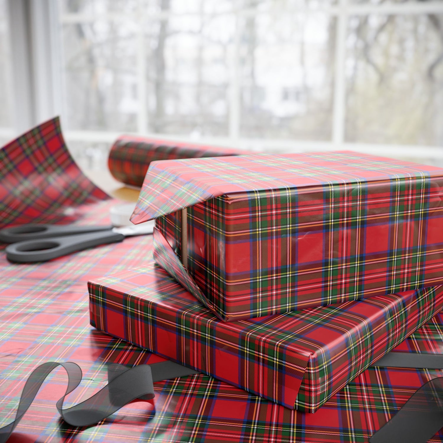 Red and green plaid gift boxes on a table with scissors.