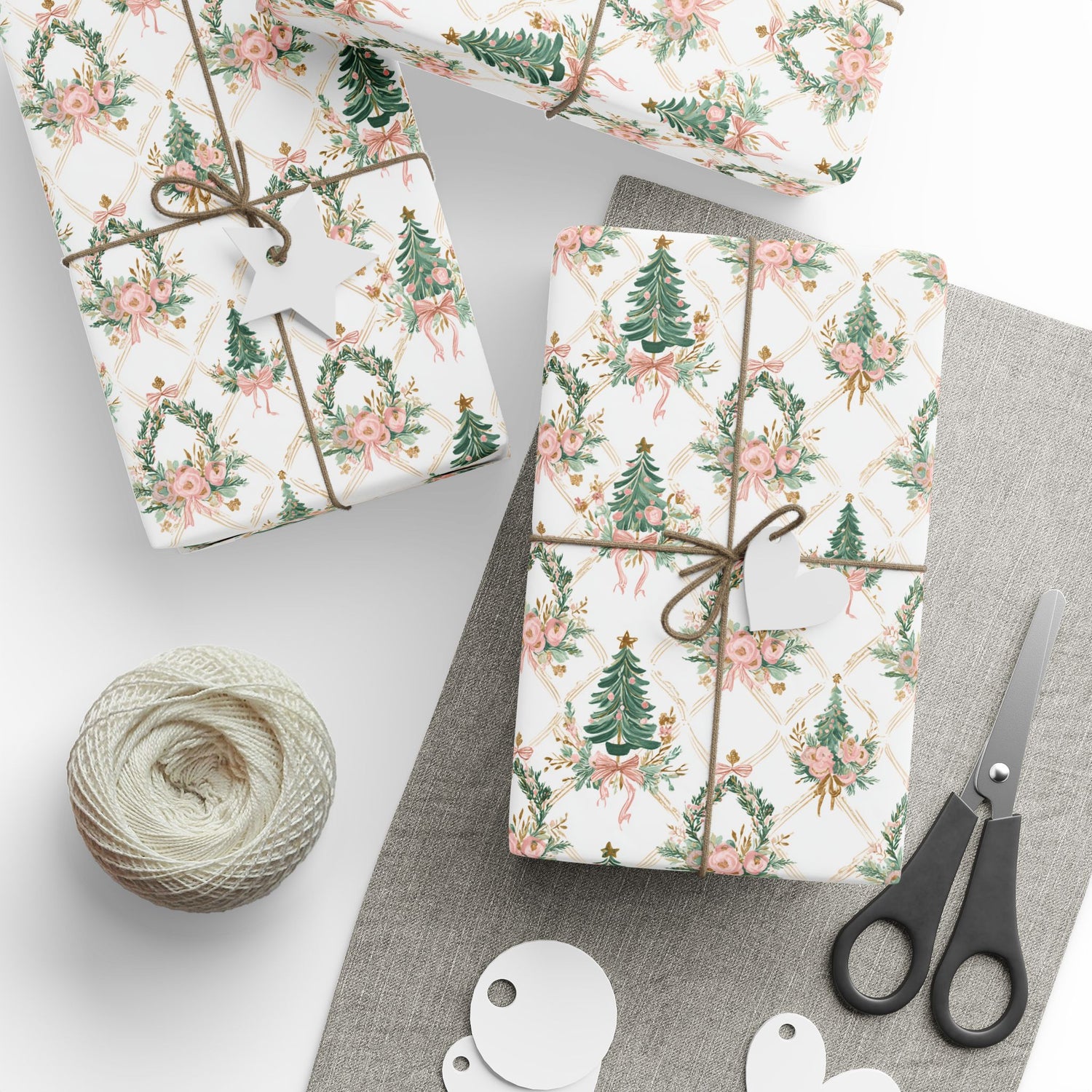 Gift wrap with floral and tree design, tied with string, on a gray surface with scissors and twine.
