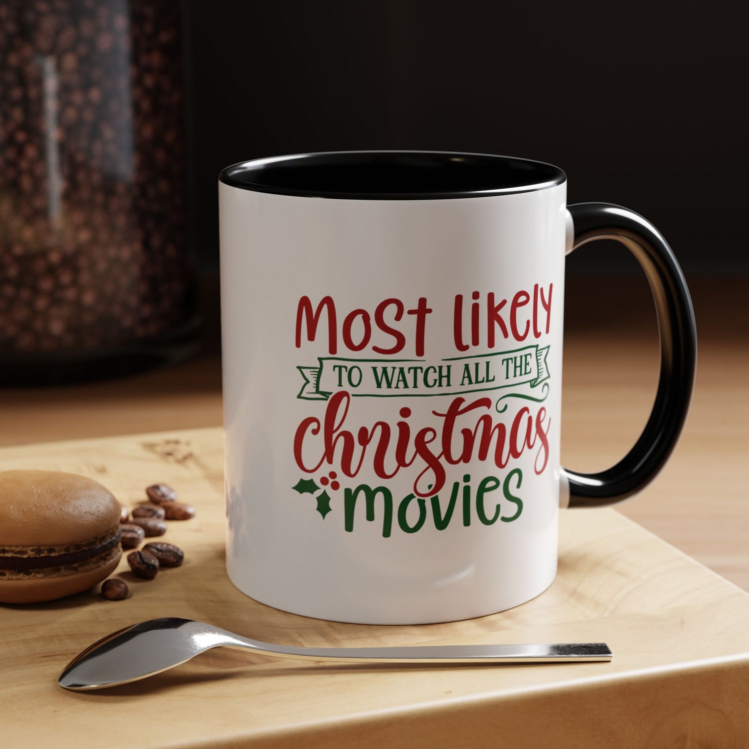 White mug with black interior and handle, featuring text about Christmas movies, on a wooden surface with coffee beans and a spoon.