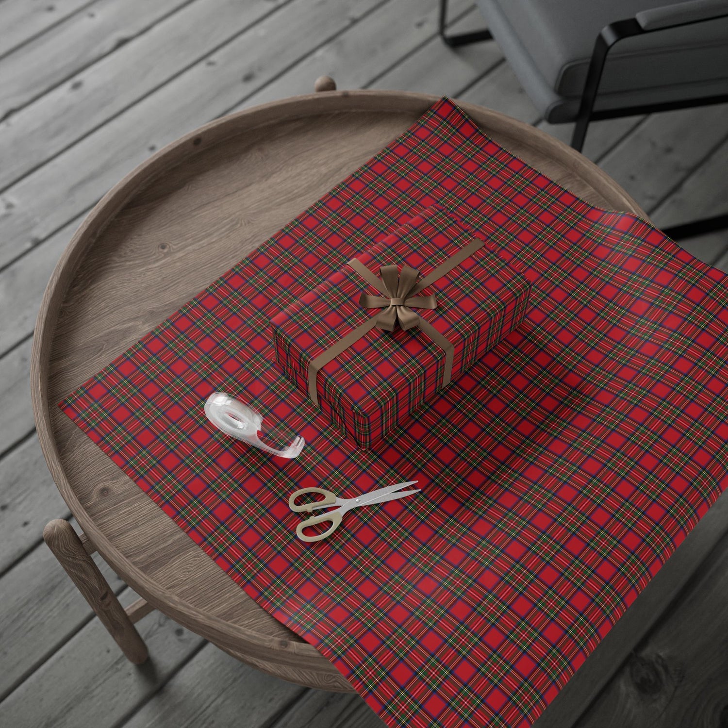 Red plaid tablecloth with a gift box, scissors, and ribbon on a wooden tray.
