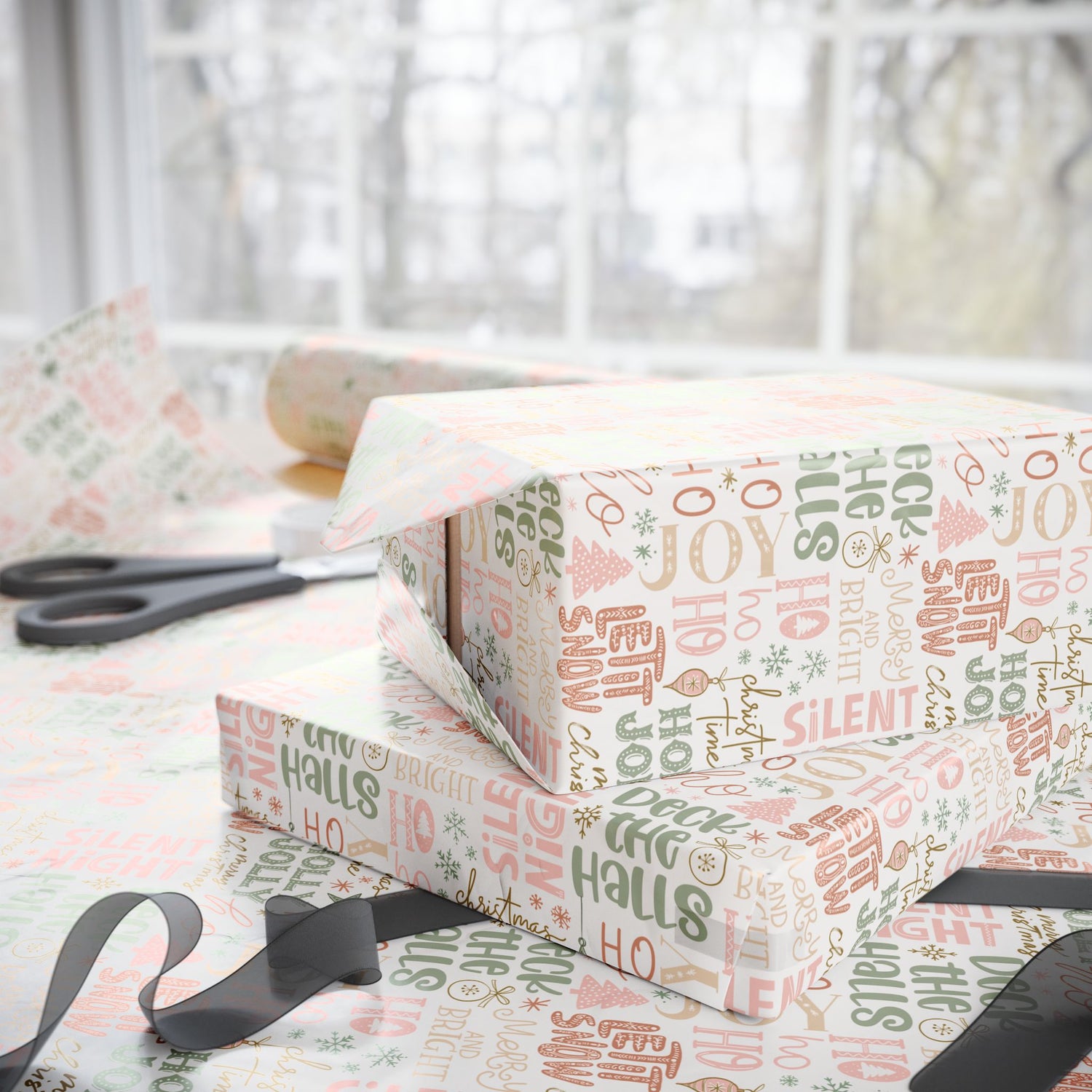 Gift box wrapped in festive paper with Christmas-themed text on a table.