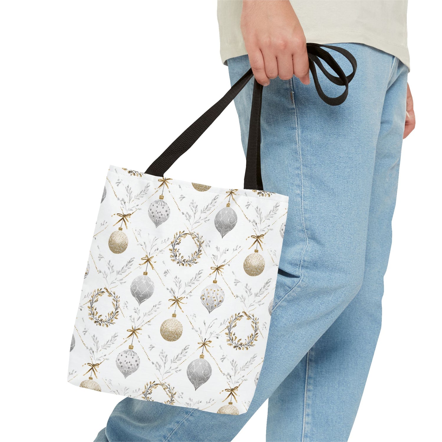Person holding a tote bag with Christmas ornament pattern on a white background