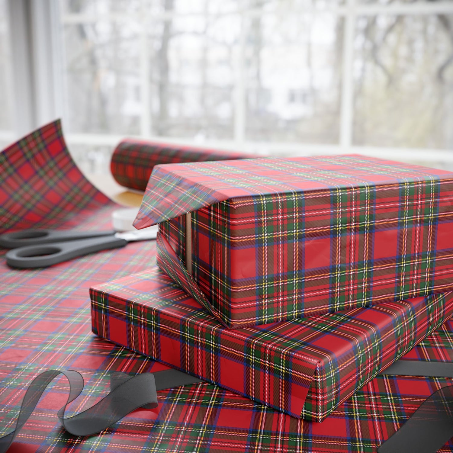 Red and green plaid gift boxes on a matching tablecloth with scissors.