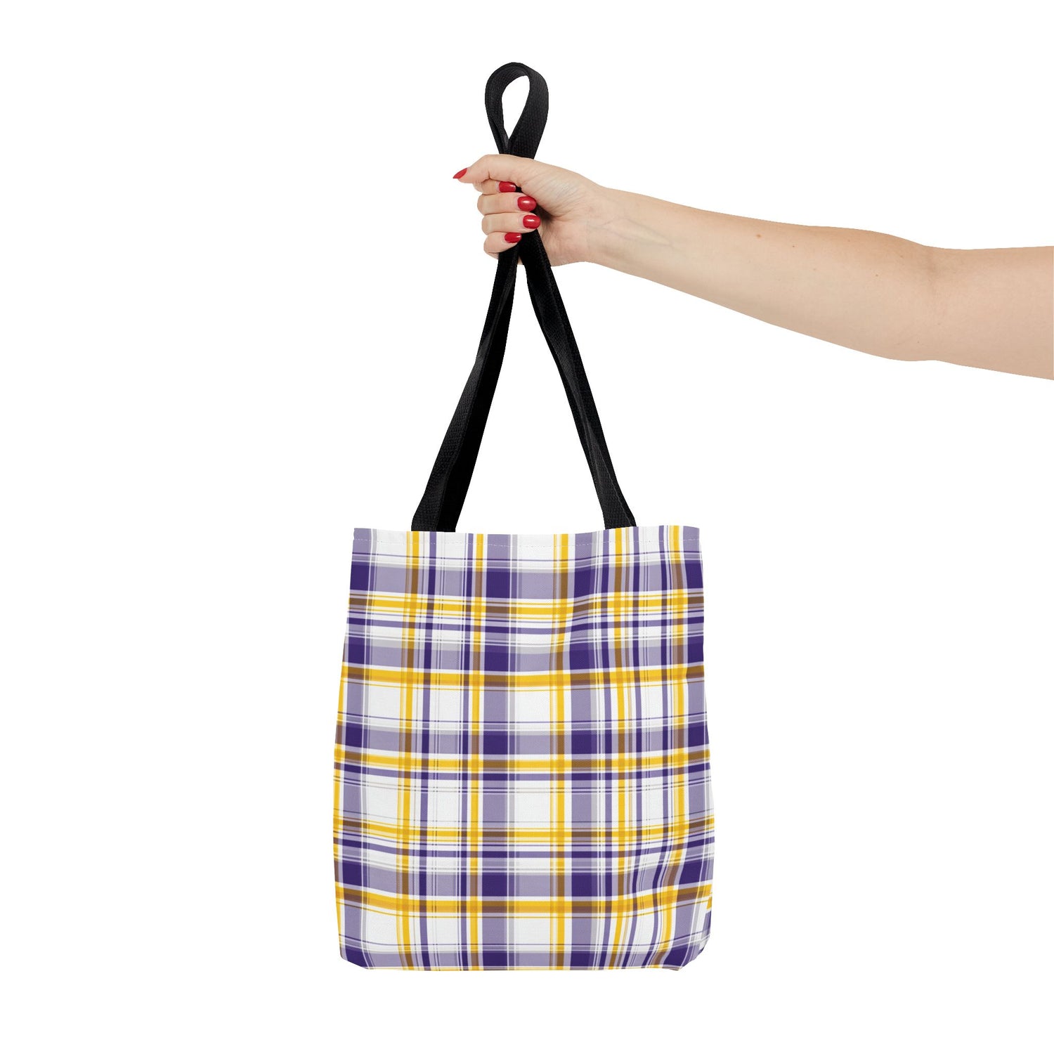 Plaid tote bag with black handles held by a hand on a white background