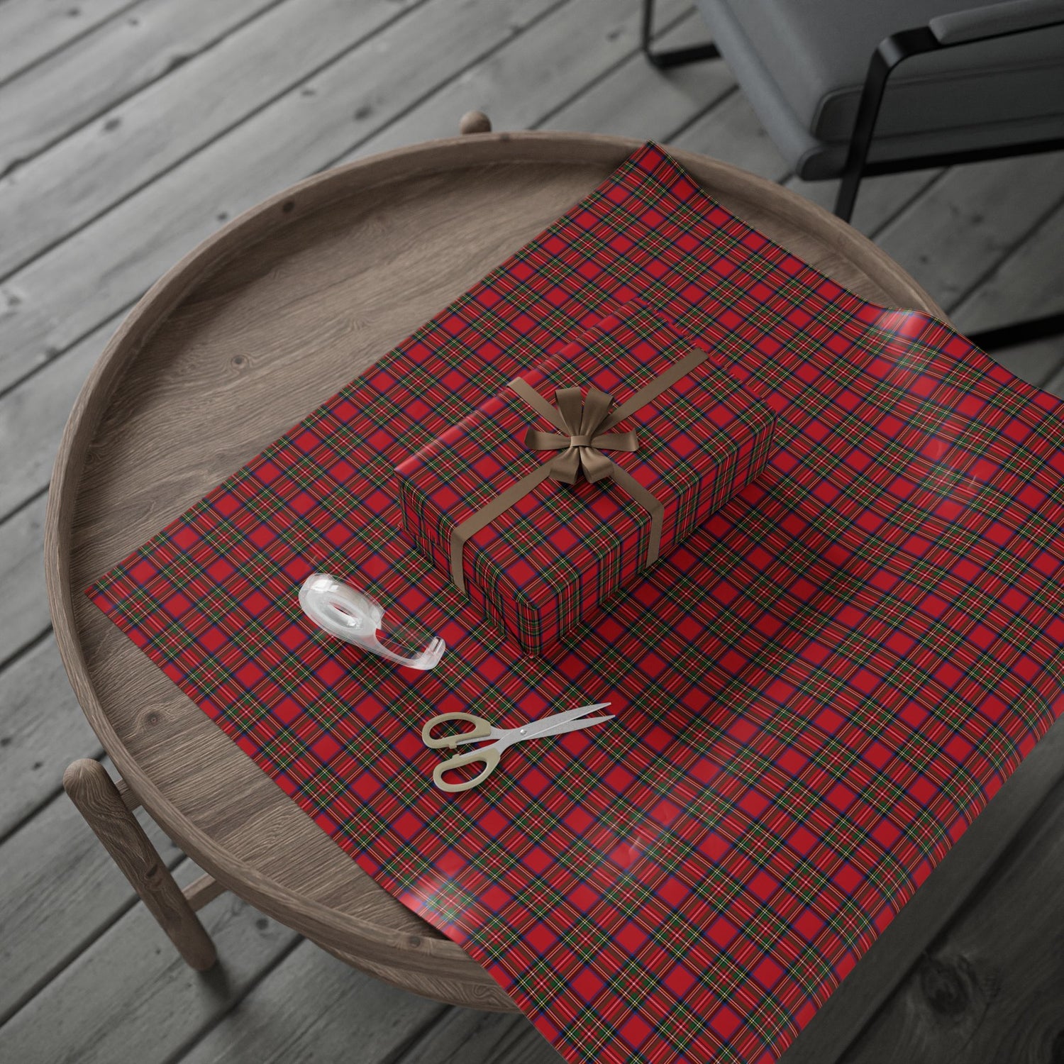 Red plaid paper with a gift box, scissors, and ribbon on a wooden tray.