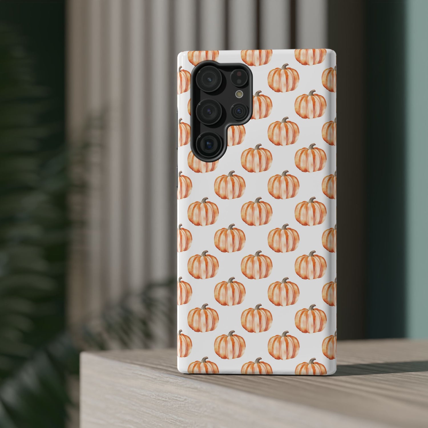 A phone case with a pattern of pumpkins on a white background, featuring a camera cutout and a black border at the top.