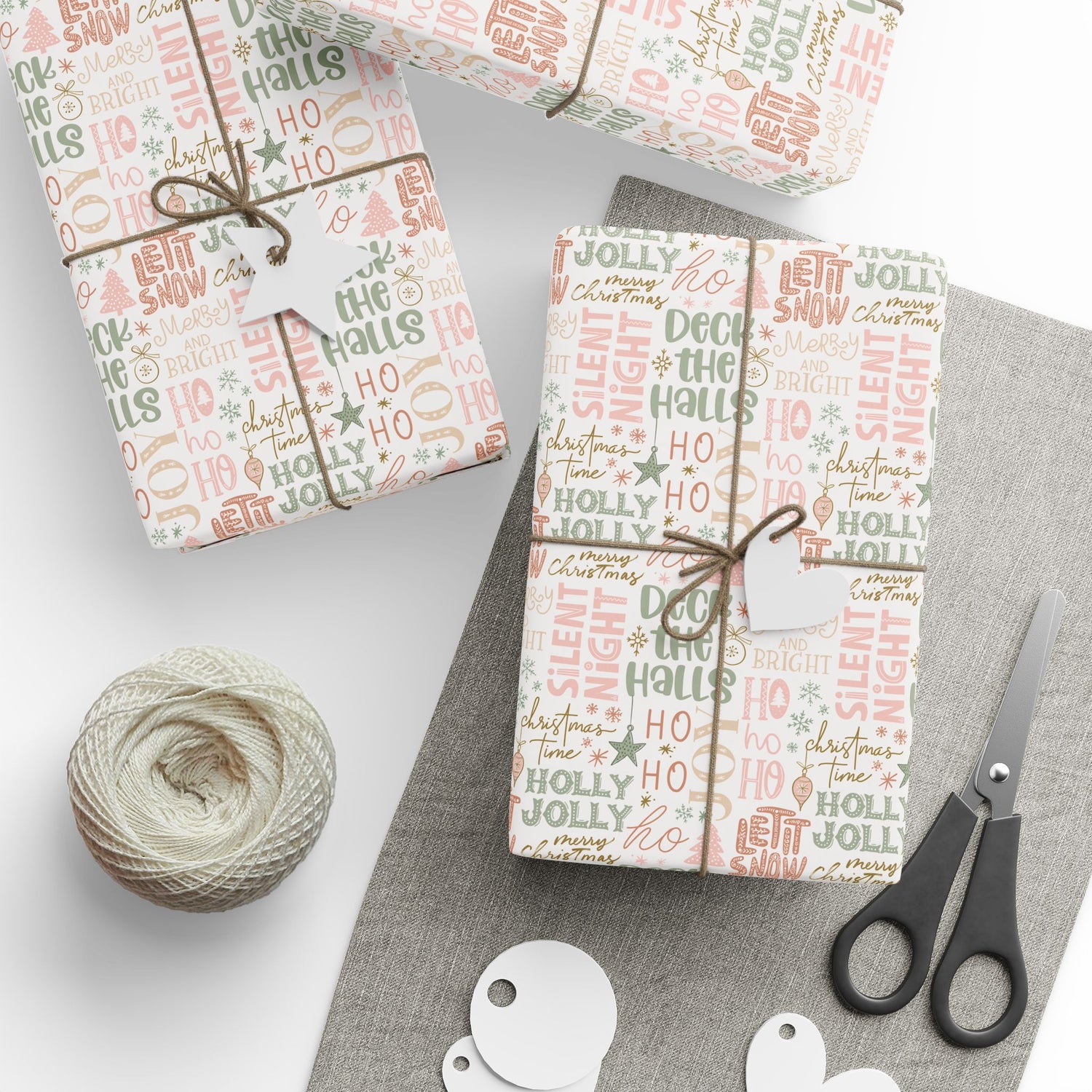 Gift boxes wrapped in festive paper with a ball of yarn and scissors on a white surface