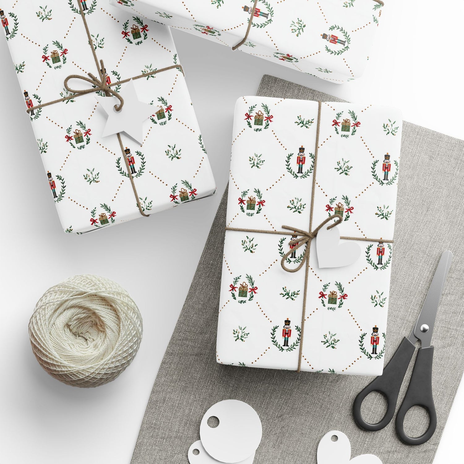Gift boxes wrapped in festive paper with a ball of twine and scissors on a gray surface.