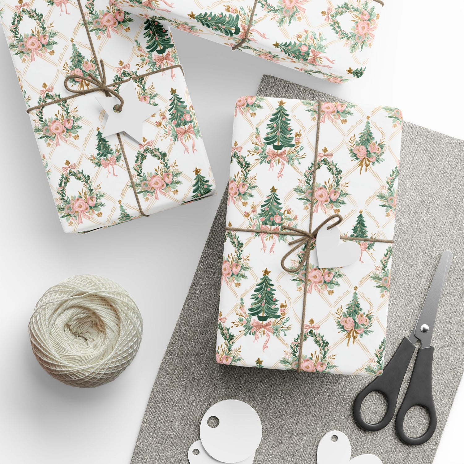 Gift boxes wrapped in floral and Christmas tree patterned paper with scissors and twine on a gray surface.