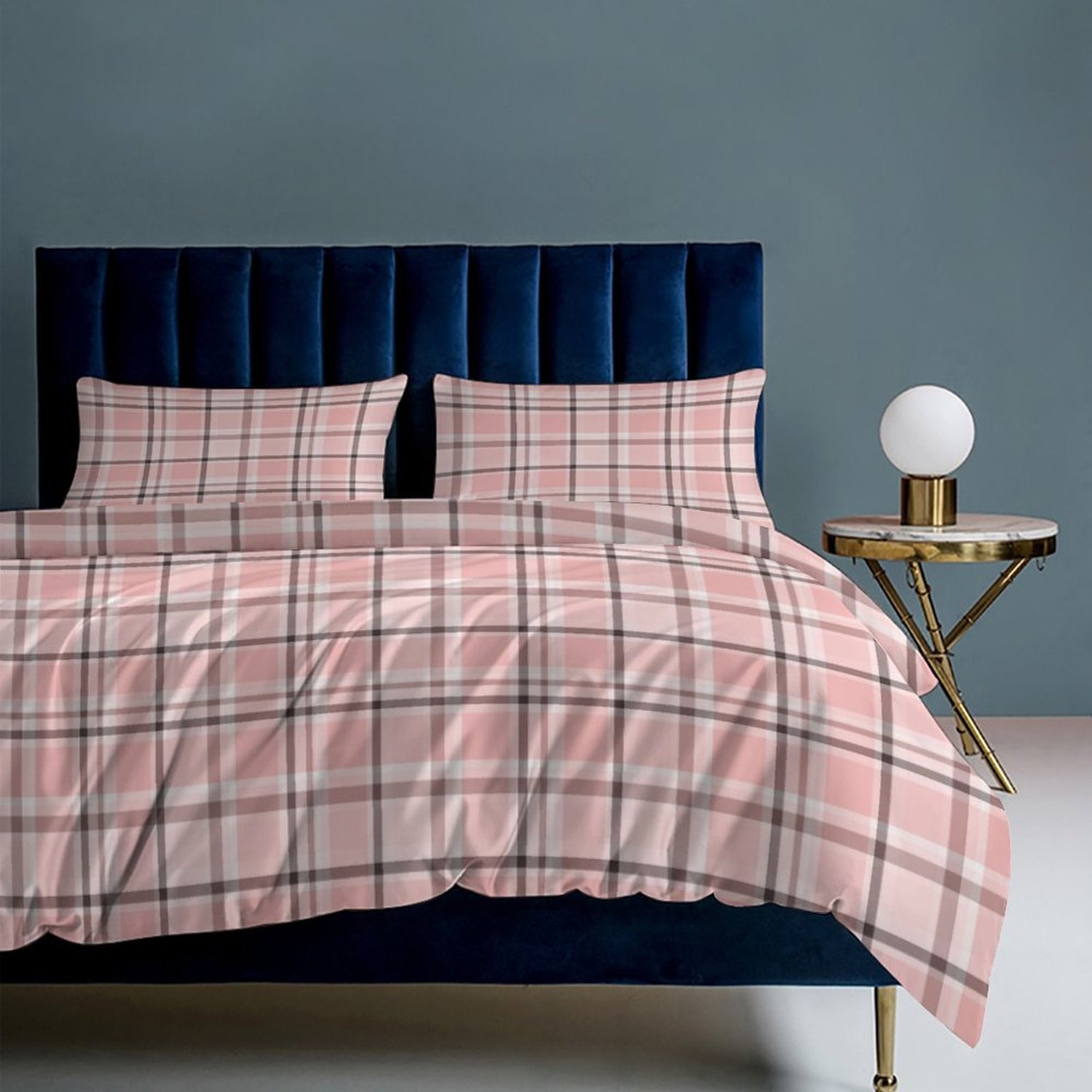 Pink plaid bedding set on a bed with a blue headboard and side table.